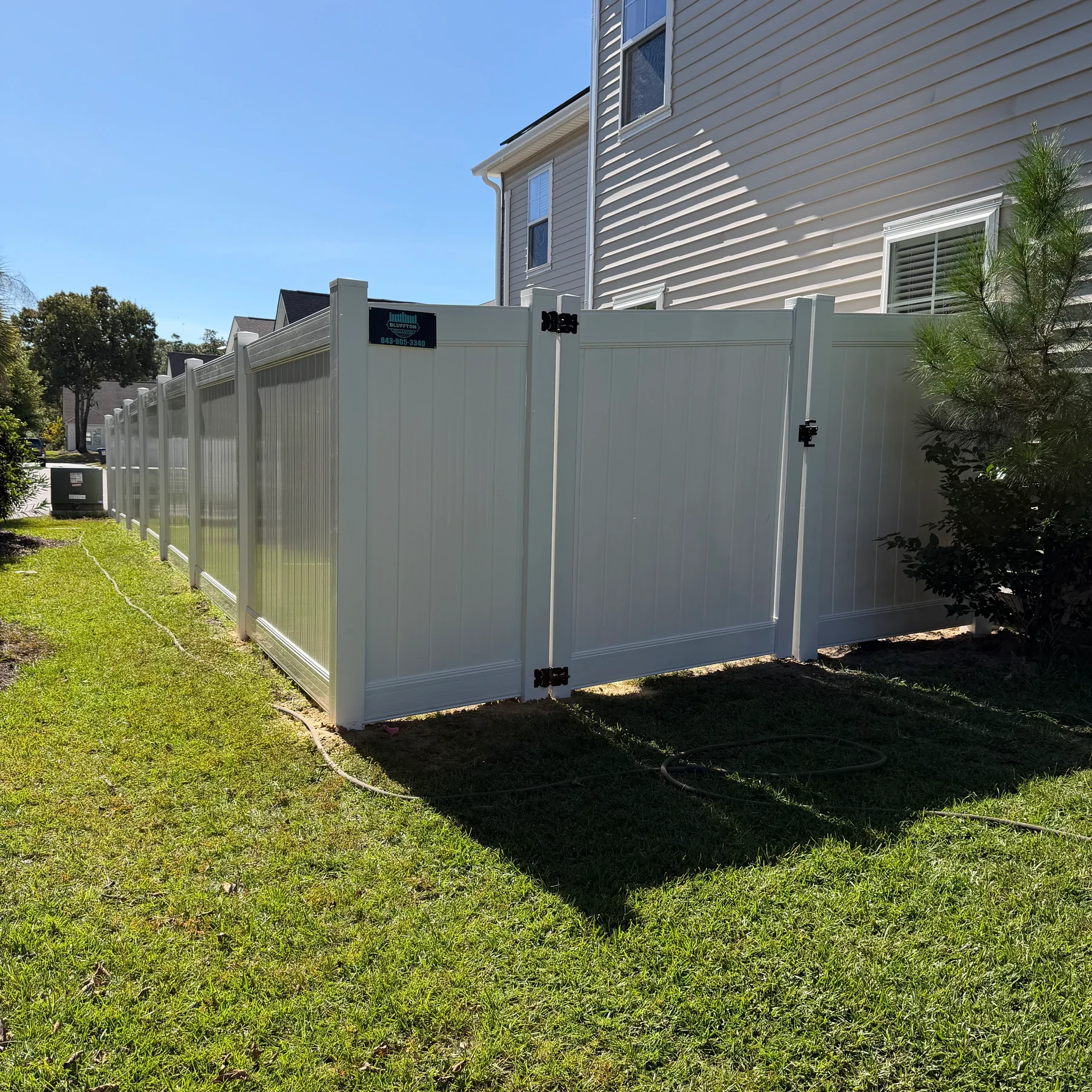 Tan vinyl privacy fence along the side of a two-story home