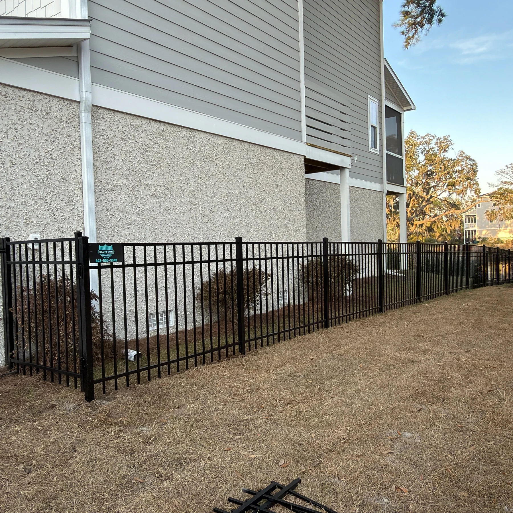 Black aluminum fence along the side of a stucco and siding home