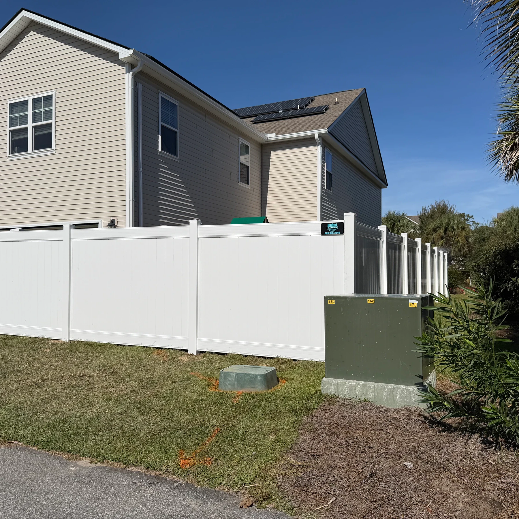 White vinyl privacy fence around the backyard of a two-story home