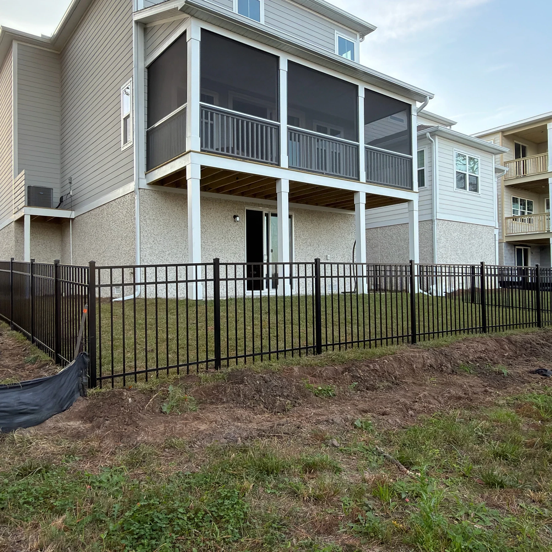 Black aluminum fence enclosing the backyard of a three-story home