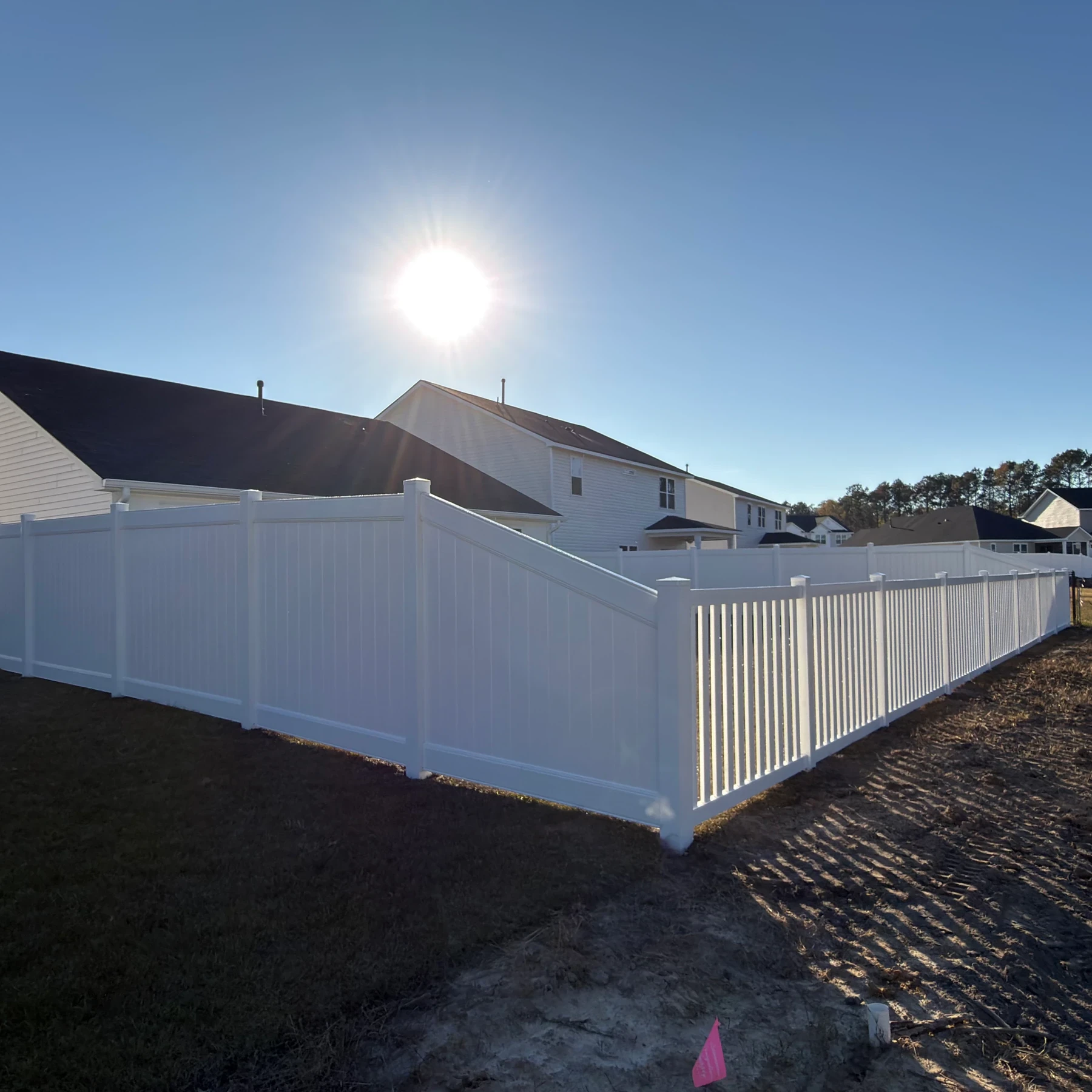 White vinyl semi-private fence behind a new home at sunset