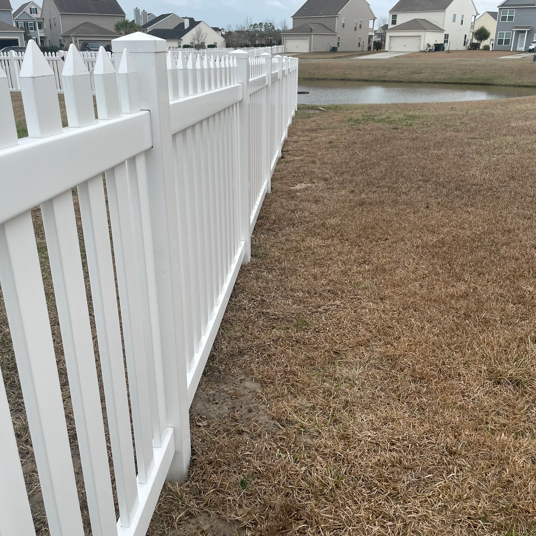 White vinyl picket fence enclosing a backyard