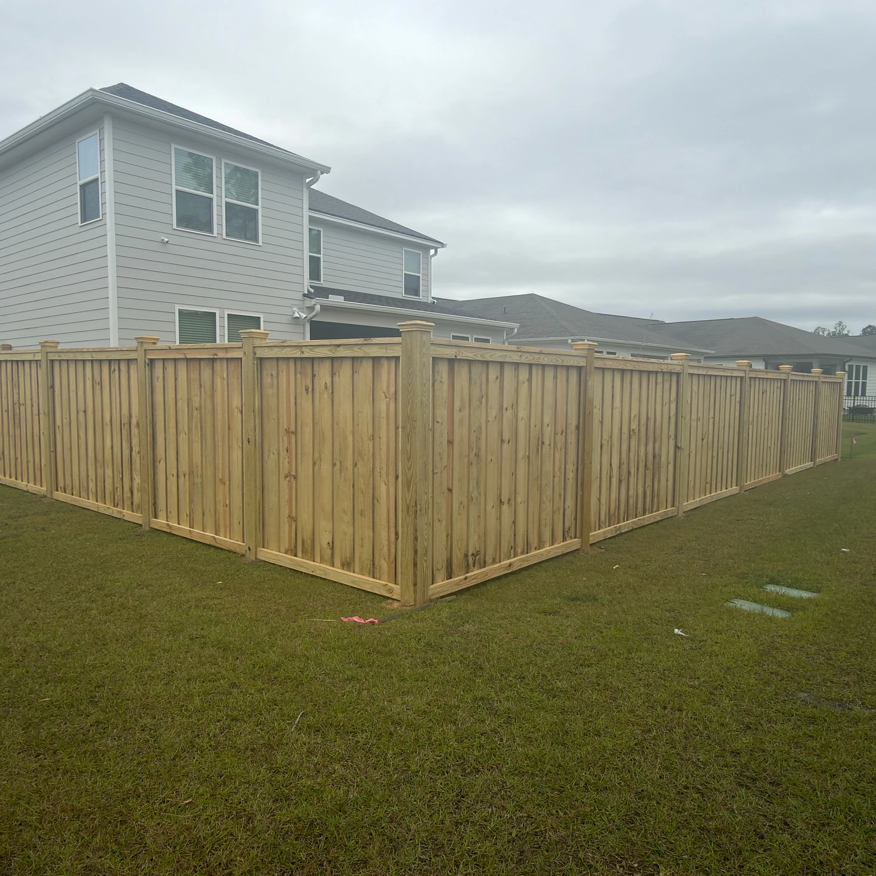 Capped wood privacy fence wrapping a backyard