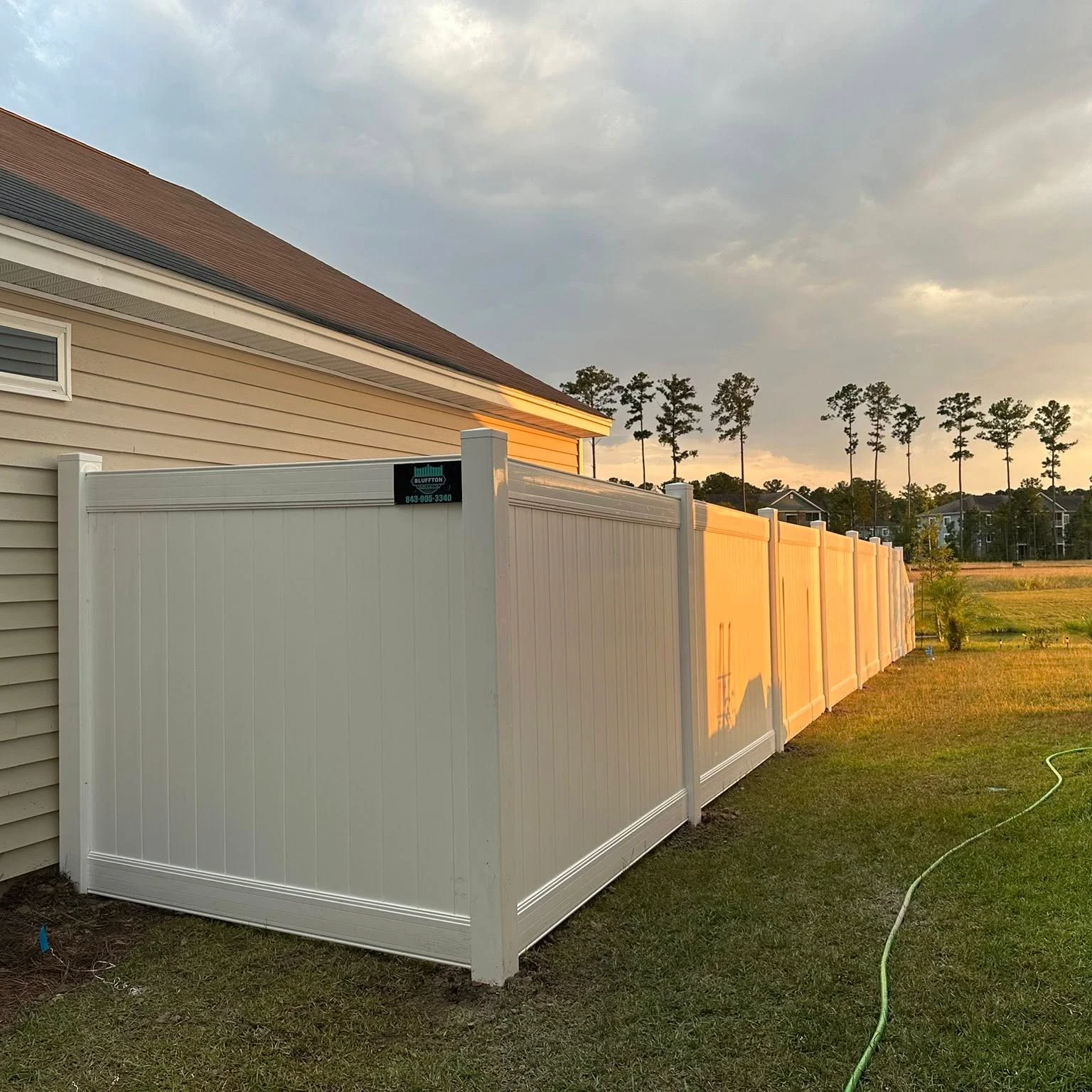 White vinyl privacy fence installed beside a home at sunset