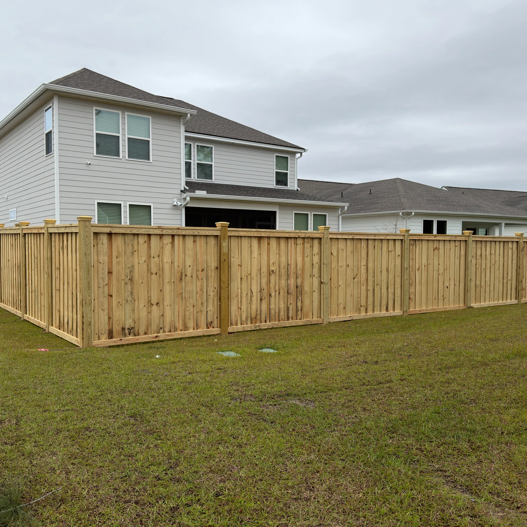 Capped wood privacy fence at the corner of a backyard