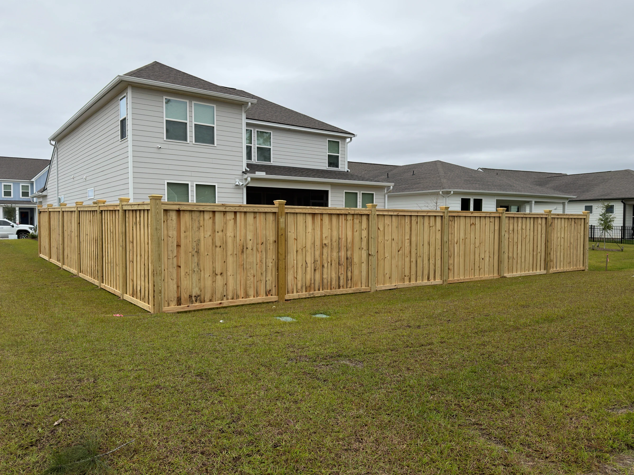 Capped wood privacy fence around the backyard of a two-story home