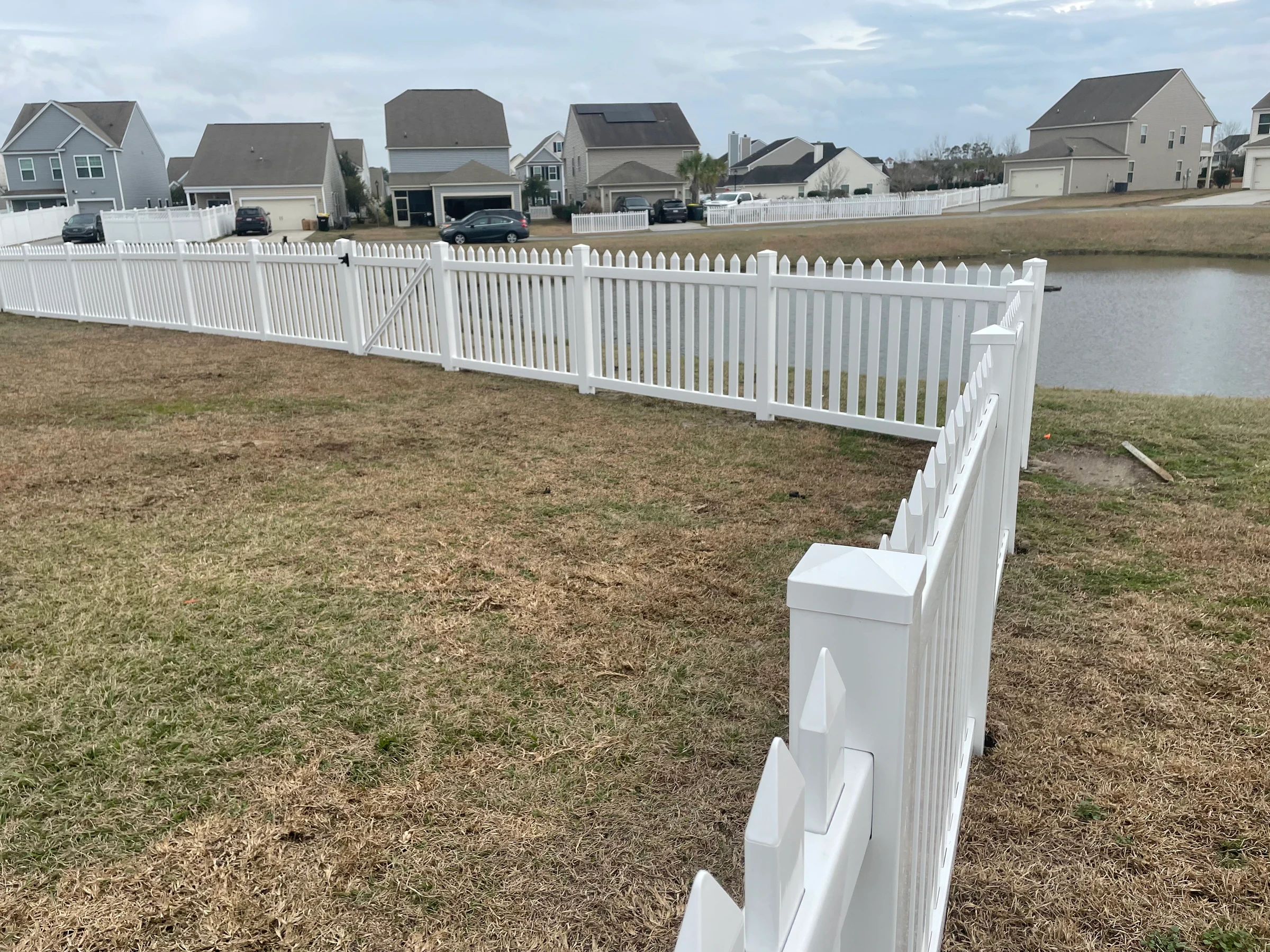 White vinyl picket fence along a pond in a Lowcountry neighborhood