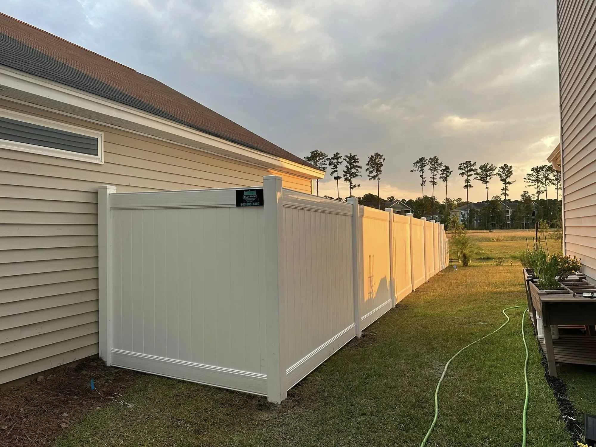 White vinyl privacy fence installed beside a Lowcountry home at sunset